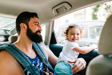 Father with little daughter sitting in a car on streets in city of Tbilisi in the capital of Georgia on sunny spring day. Dad and girl travel on excursion in old town.