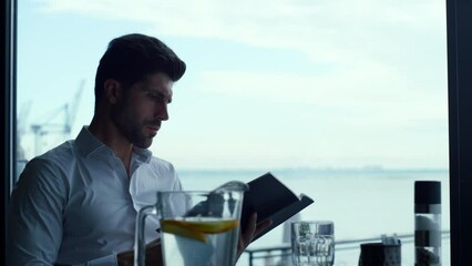Relaxed man customer reading wine list in panoramic luxury lounge bar portrait