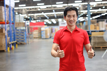 Portrait of warehouse workers young asian man standing and showing thumb up with happy smiling face and confident in retail warehouse logistics, distribution center