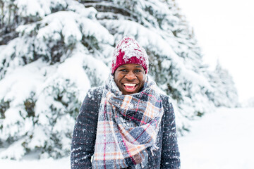 african american handsom man in red hat and stylish plaid coat look at camera with toothy snow- white smile outdoor in park