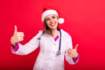 Fototapeta na wymiar A smiling woman doctor in a white coat in a Santa Claus hat shows the class and looks into the camera