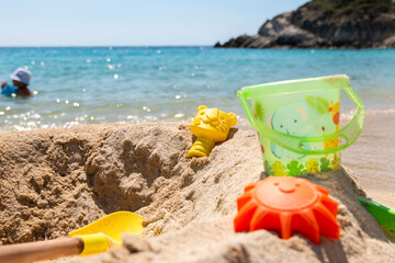 Children plastic toys using playing on sand at beach. Summer, vacation time and child development