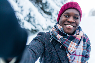 african man taking picture by smartphone selfie outdoors in winter forest