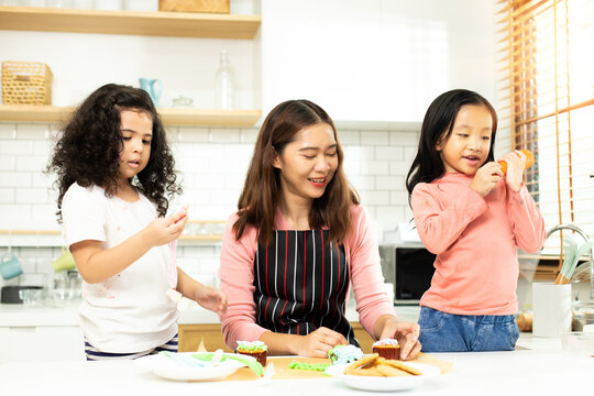 Group Of Diverse Family, Asian And Arab Preschool African Arab Kid Person Make Cake Cooking In Kitchen, Mother Prepare Decoration Pretty With Fun Educate On Snack. Cream Mess All Over Face, Copy Space