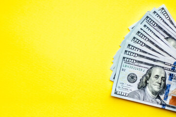 US dollars on the right side, place for text, yellow background, flat lay, hundred banknotes