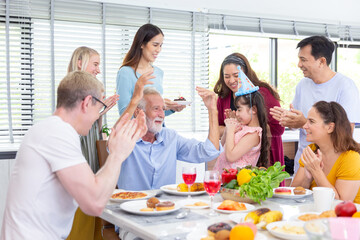 surprise granddaughter with chocolate cake for birthday party with group of happy and smile family at home after dinner meal with many food for celebration