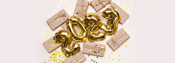 2023 number made from foil golden balloons and gift boxes. New year background.