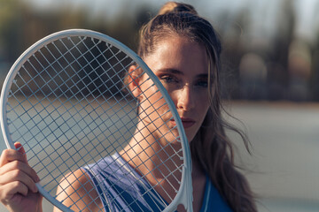 Chica joven en traje de tenis sobre la cancha copn raqueta blanca