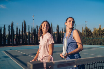 Dos chicas vestidas con ropa de tenis rosa y morada paseando juntas y haciendose selfies con...