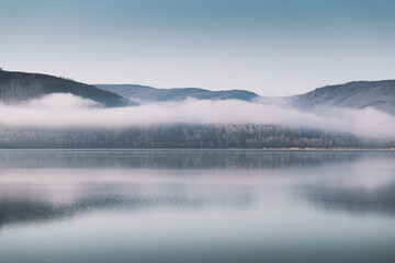 Mountain lake with clouds in foggy morning. Autumn landscape.