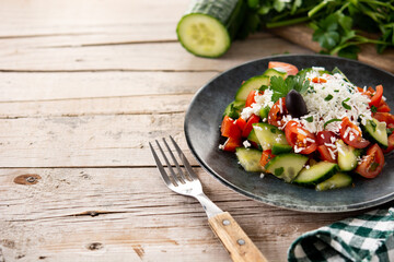 Traditional Bulgarian shopska salad with tomato,cucumber and bulgarian sirene cheese on wooden table	