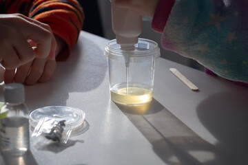 Children make slime themselves from glue and thickener, kids play with homemade yellow slime