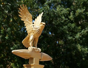 Reproduction dorée d'un aigle de Jupiter dressé sur un foudre et aux ailes déployées, au sommet d'une enseigne de l'armée romaine, sur fond de végétation