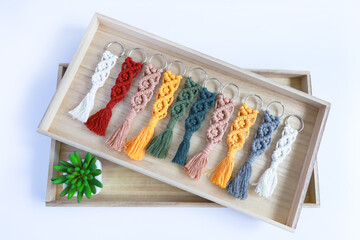 Hand made cotton macrame key chains  of different colour on green book with eukaliptus leaves © Aree