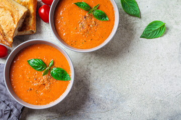 Traditional gaspacho in gray bowl. Summer tomato soup with basil.