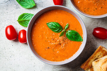 Traditional gaspacho in gray bowl. Summer tomato soup with basil.