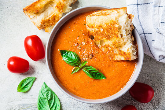 Traditional gaspacho in gray bowl. Summer tomato soup with basil.