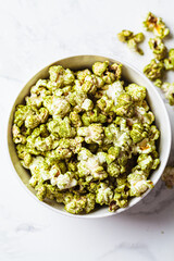 Green spirulina popcorn in white bowl. Alternative food, healthy dessert, plant-based diet.