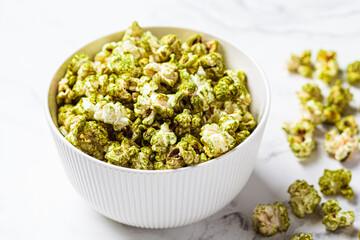 Green matcha popcorn in white bowl. Alternative food, healthy dessert, plant-based diet.