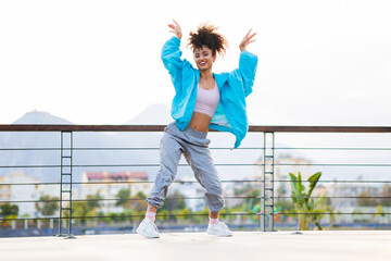 latin hispanic woman dancing outdoors at sunset in street