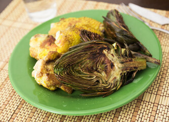 cooked fried chicken wings and halves artichokes on green plate