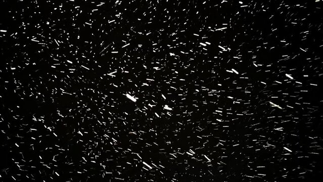 Night snowstorm. Blustery snowfall moving quickly towards the camera. Forward motion through a snow blizzard. Black background. Falling snowflakes, textured pattern. Footage. Winter season. Xmas.