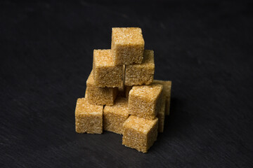 Cane sugar on a black background. Brown refined cane sugar.