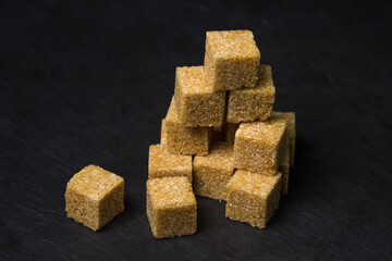 Cane sugar on a black background. Brown refined cane sugar.