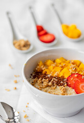 Detail of a bowl of porridge with strawberry, mango and toppings