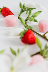 Branch composition with flowers, strawberries and candies. Food styling. Spring comfort food composition.
