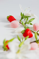 Branch composition with flowers, strawberries and candies. Food styling. Spring comfort food composition.