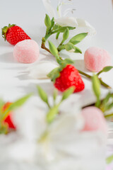 Branch composition with flowers, strawberries and candies. Food styling. Spring comfort food composition.