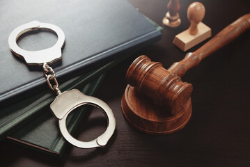 Arrest concept. Metal handcuffs near judge gavel