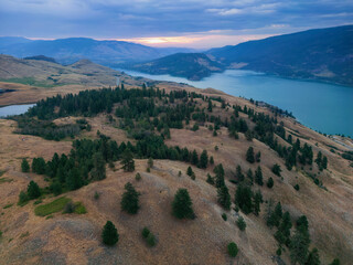 Obraz premium Aerial View of Canadian Landscape with Kalamalka Lake and Mountains. Colorful Cloudy Summer Sunrise. Near Vernon, Okanagan, BC, Canada. Nature Background