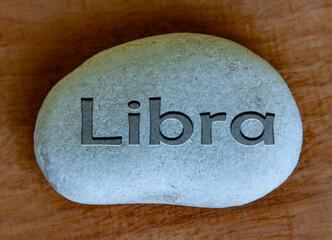 Libra zodiac sign text engraved on a stock with wooden background. Zodiac sign concept