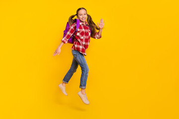Photo of adorable sweet schoolkid dressed plaid shirt jumping high running fast isolated yellow color background
