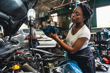 Mechanic using a cloth to clean the dipstick in the garage.