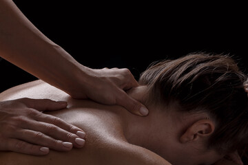 Fototapeta na wymiar masseur girl makes a massage close-up on a dark background. close-up massage