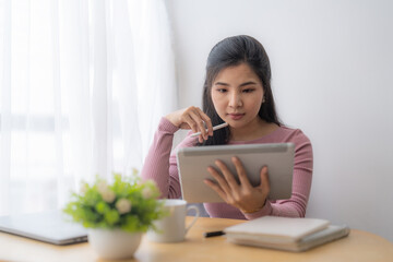 Young asian woman using digital tablet at home. Online learning, home school concept.
