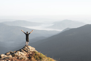 Alone tourist on the edge of the cliff against the backdrop of an incredible sunrise mountains...