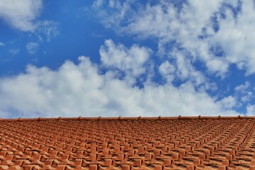 perspective view of a tiled roof under a blue cloudy sky