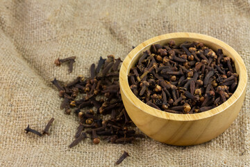 Cloves in wooden bowl on sackcloth. Herbal cloves have a fragrant and spicy flavor.