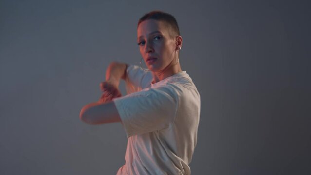 Dancing stylish girl with short haircut performing alluring contemporary dance at camera in studio. ProRes codec
