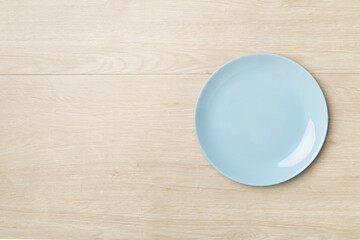 Empty round plate on wooden background, top view