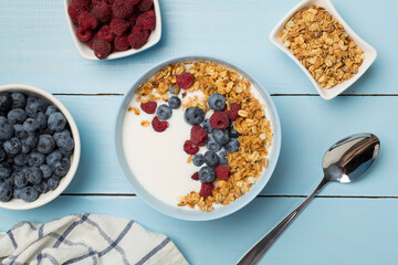 Bowl with granola, yogurt and fresh berries on wooden background, top view