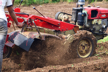 Farmers cultivate land with tractor or power tiller machine, modern agriculture, tractor
