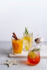 Three colorful Christmas cocktails in glasses on white table. Assortment of fresh holiday drinks. Strawberry Mojito, orange punch cocktail, tropical mule.