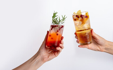 Woman's hands holding сranberry gin tonic and tropical mule on white background. Fresh holiday...