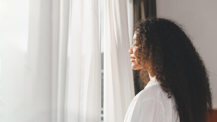 Portrait of charming pretty cute lovely lady satisfied glad inspired cheerful positive. Happy young mixed race female with wavy hair enjoying summer view through window. African lady in vacation.