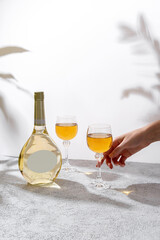 Glasses and bottle of white wine with blank label on light background. Wine making and wine degustation concept. Free space for your text